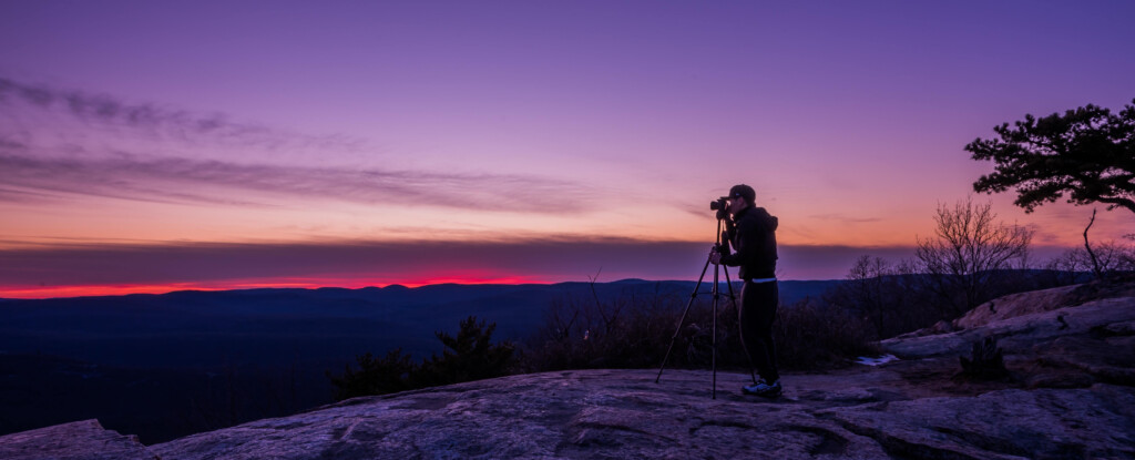 man using tripod for photography at sunset