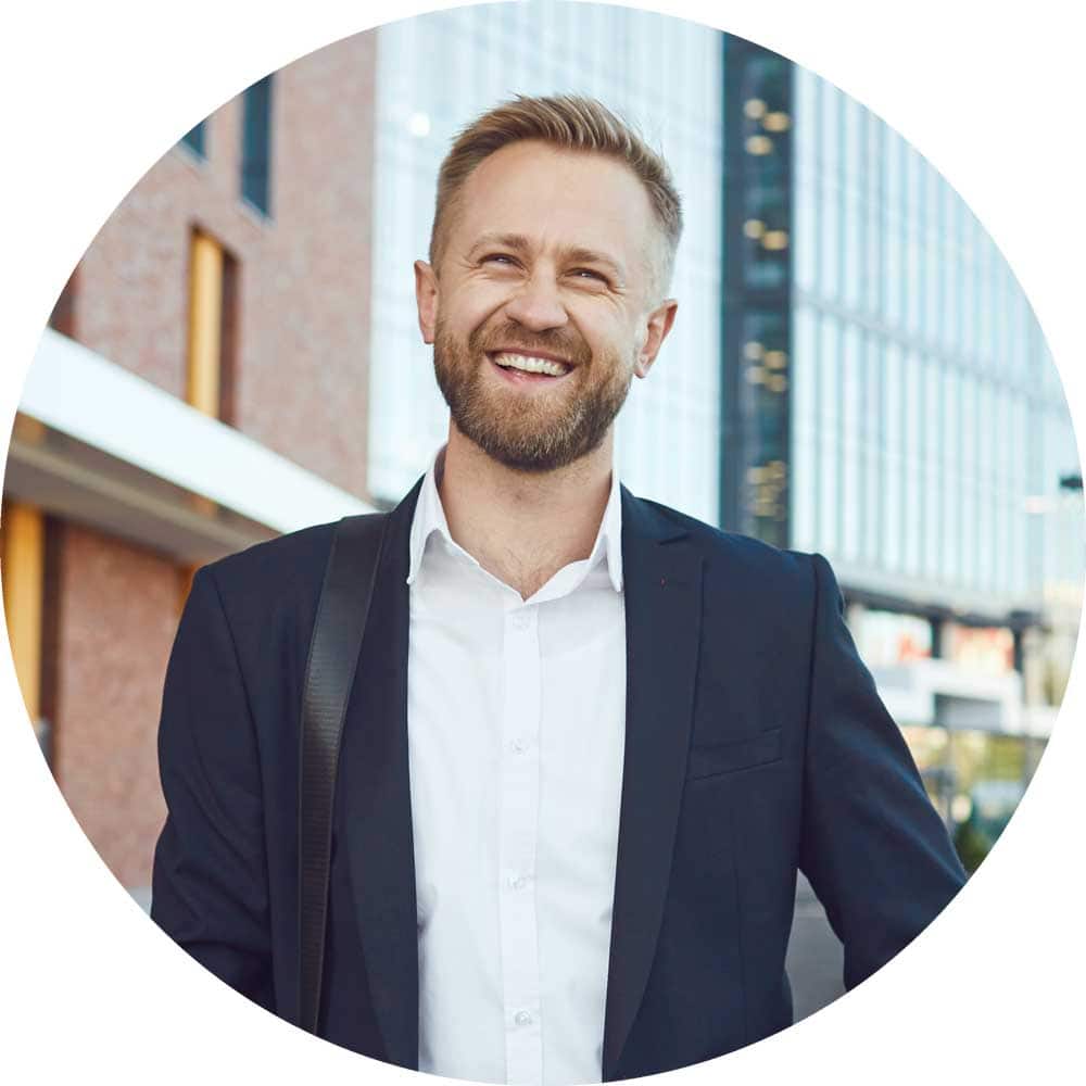 A smiling businessman is standing on the street.